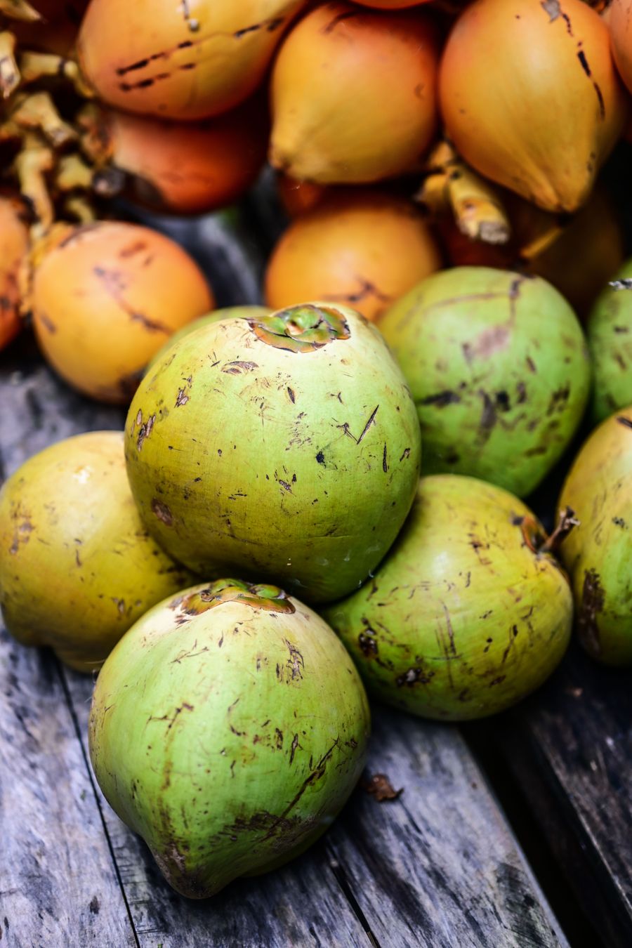 Timbunan kelapa muda hijau di kaunter pasar berlatar jingga