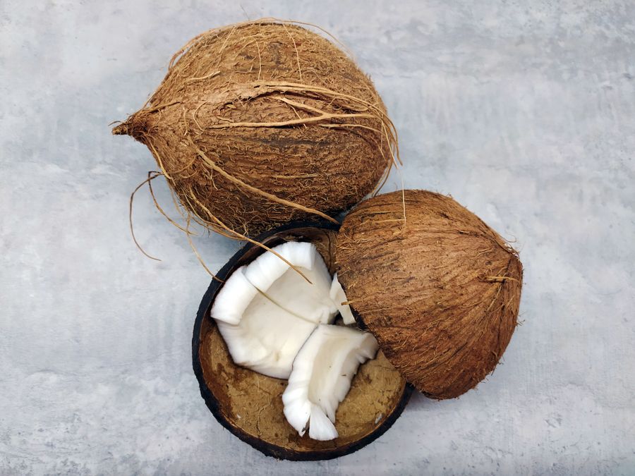 Kelapa coklat penuh dan kelapa dibelah menunjukkan isi putih